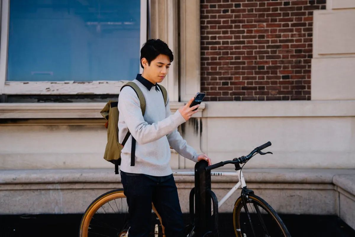 Un jeune homme regarde son téléphone à côté de son vélo.